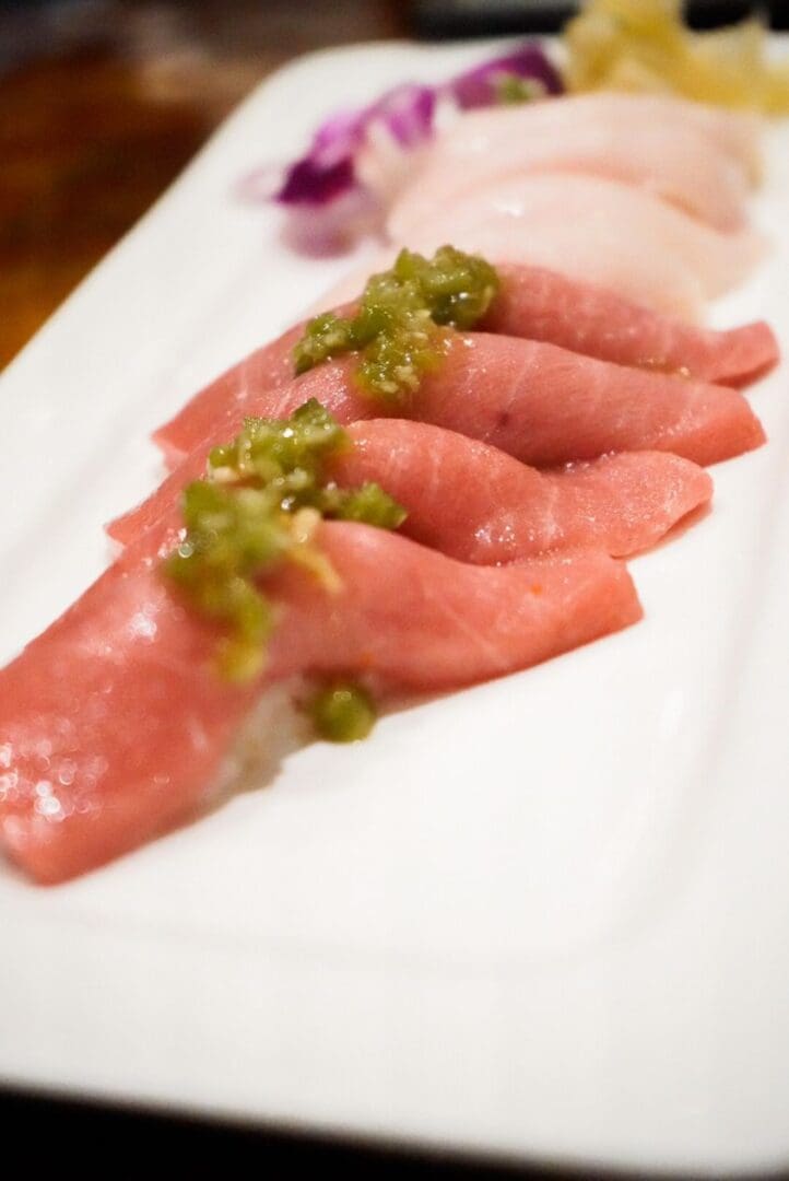 A plate of meat with green sauce on it.